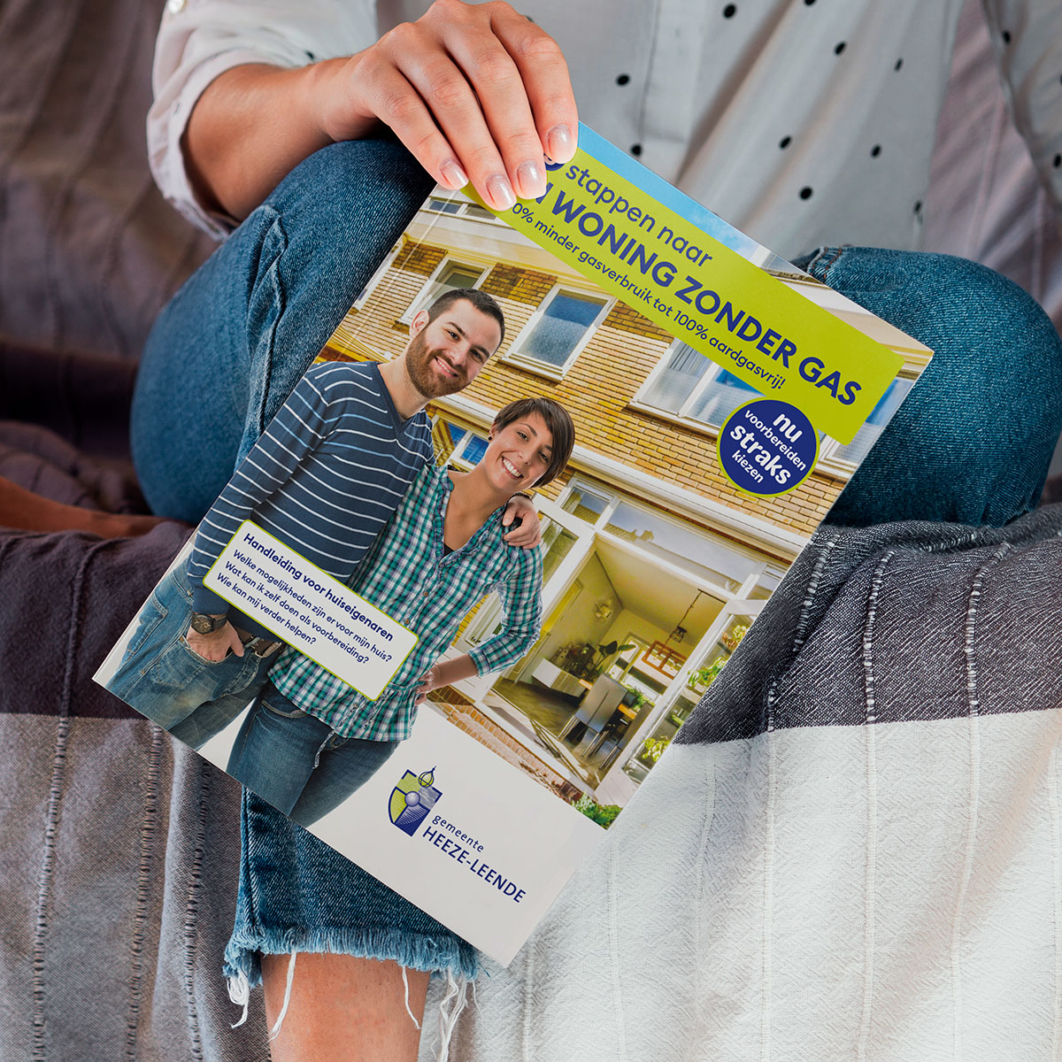 Vrouw op de bank houdt handleiding In 5 stappen naar een woning zonder gas vast