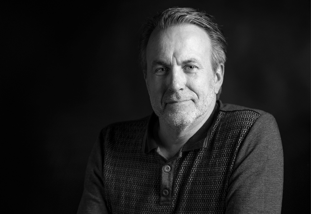 zwart-witte foto van Wim: man van middelbare leeftijd die je glimlachend aankijkt