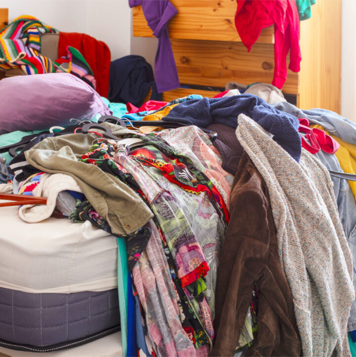 Grote stapel kleren door elkaar op het bed